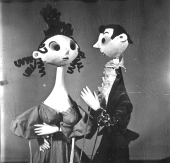 Černobílý obrázek dvou kubánských loutek, pán a paní ve večerních oblecích spolu hovoří.