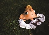 Hurvínek ležící na zádech s rukama za hlavou v trávě.