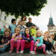 Skupina dětí a lektorem na výletě v Pardubicích, foceno na Pernštýnském náměstí, v pozadí Zelená brána.