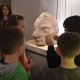 Děti plnící úkol u velké sochy ve tvaru hlavy. 